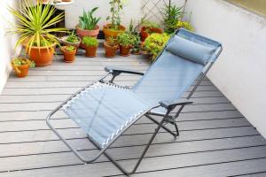 une chaise bleue assise sur une terrasse couverte avec des plantes en pot dans l'établissement T2 Tout Confort avec terrasse- Métro Saint Cyprien, à Toulouse