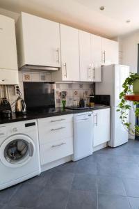 - une cuisine avec des placards blancs et un lave-linge dans l'établissement T2 Tout Confort avec terrasse- Métro Saint Cyprien, à Toulouse