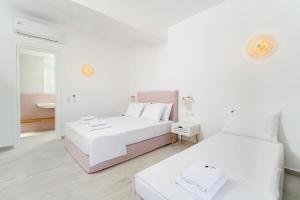 um quarto branco com 2 camas e um espelho em Filoxenia Luxury Apartments em Potos