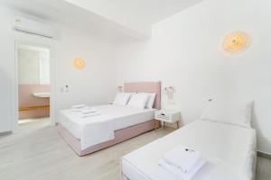 a white bedroom with two beds and a mirror at Filoxenia Luxury Apartments in Potos
