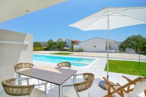 a patio with a table and chairs and an umbrella at Filoxenia Luxury Apartments in Potos +44 photos