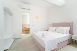 um quarto branco e rosa com uma cama e uma casa de banho em Filoxenia Luxury Apartments em Potos