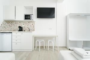 a kitchen with white cabinets and a table and stools at Filoxenia Luxury Apartments in Potos
