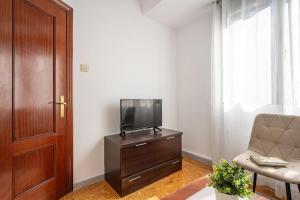a living room with a television on a dresser with a chair at Apartamento Luca in Gijón