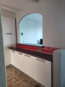 une cuisine avec des placards blancs et un comptoir rouge dans l'établissement Maison au calme vue montagnes, à Vence
