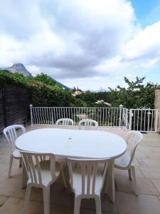 una mesa blanca y sillas en un patio en Maison au calme vue montagnes, en Vence