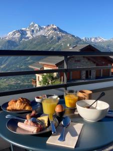Hôtel Alpen Lodge في لا روزيير: طاولة عليها طعام مع جبال في الخلف