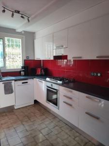 a kitchen with white cabinets and red walls at Maison au calme vue montagnes in Vence