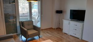 un salon avec une chaise et une télévision dans l'établissement Apartment Martin, à Gevgelija