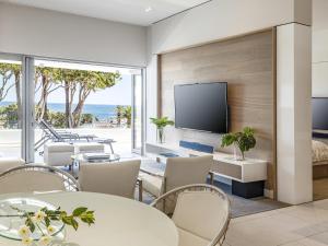 sala de estar con mesas y sillas y TV de pantalla plana en South Beach Camps Bay Boutique Hotel, en Ciudad del Cabo