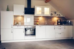 uma cozinha branca com armários e electrodomésticos brancos em Ferienwohnung Sonnenuntergangsidyll Harriersand em Schwanewede