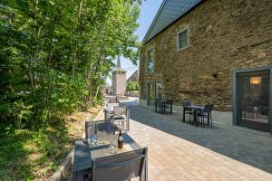 een patio met tafels en stoelen naast een bakstenen gebouw bij B&B - La Maison des Sottais in Burg-Reuland