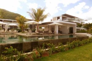 a villa with a swimming pool in front of a house at Latitude Sea Front Luxury Apartment in Rivière Noire