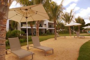a group of chairs and an umbrella in front of a house at Latitude Sea Front Luxury Apartment in Rivière Noire