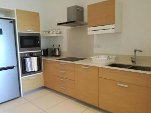 a kitchen with wooden cabinets and a white refrigerator at Latitude Sea Front Luxury Apartment in Rivière Noire