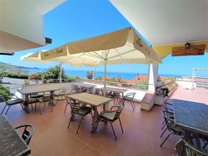 un patio con tavoli, sedie e vista sull'oceano di Alabe Hotel a Tresnuraghes