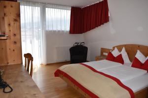 a bedroom with a large bed with red pillows at Hotel Kleißl in Oberperfuss