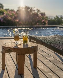 Résidence U Frusteru في بروبريانو: طاولة خشبية عليها مشروبين بجانب المسبح