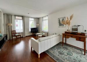 a living room with a white couch and a piano at Center Appartement Apeldoorn in Apeldoorn