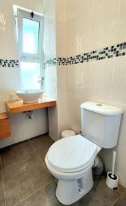a bathroom with a white toilet and a sink at 2 bedroom ground floor apartment in Kalogrea