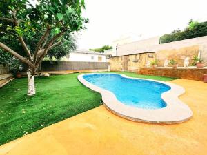 a swimming pool in a yard with a tree at Casa de vacaciones en castelldefels ¡tranquilidad y piscina! in Castelldefels