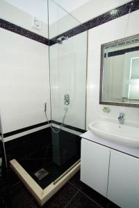 ヴロラにあるApartament Deti Bluのガラスのシャワーと洗面台を備えたバスルーム