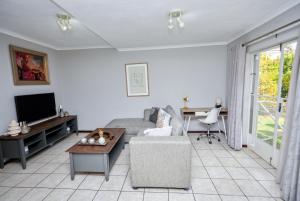 a living room with a couch and a tv and a table at Cosy Hatfield Apartment in Pretoria +7 photos
