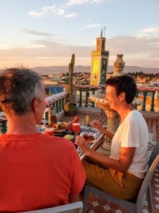 due persone sedute a un tavolo sul tetto di un edificio di Riad Malak a Meknès
