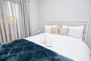 a bedroom with a white bed and a window at Cosy Hatfield Apartment in Pretoria