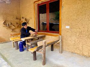 a man sitting at a picnic table in front of a building at Lý Đành Homestay in Quang Ba