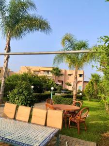 un patio con mesa, sillas y palmeras en Maison de vacances avec piscine privèe en Fez