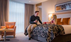 Un uomo e una donna seduti su un letto in una stanza d'albergo di Clayton Hotel Cork City a Cork