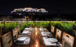 - une longue table avec des verres à vin et des lumières sur le balcon dans l'établissement 360 Degrees, à Athènes