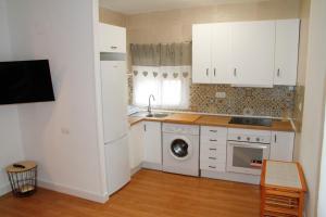 a kitchen with white cabinets and a washing machine at Antich Apartment Deltebre in Deltebre