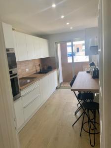 a kitchen with white cabinets and a table with chairs at Le Roxane 2 bedroom apartment in the city-center of Antibes in Antibes