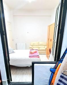 um pequeno quarto com uma cama e um sofá em Habitación privada en departamento familiar a pasos de la playa em San Sebastián
