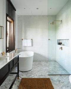 een badkamer met een bad en een glazen douche bij Siri Sala Private Thai Villa in Bangkok