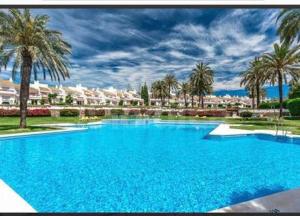 una gran piscina azul con palmeras y edificios en Cozy apartment next to Hard Rock Hotel, en Marbella