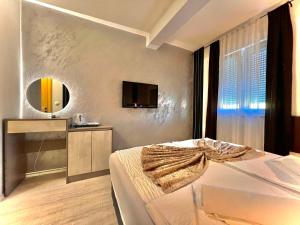 Hotel & Spa Villa Luxe في موستار: غرفة نوم مع سرير وتلفزيون على الحائط