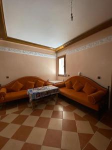 un soggiorno con 2 divani arancioni in una camera di Appartement Sidi Bouzid a El Jadida