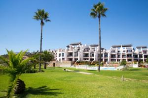 un parco con palme e un grande edificio di LUXURY Casares del Mar D BJ2 a Casares