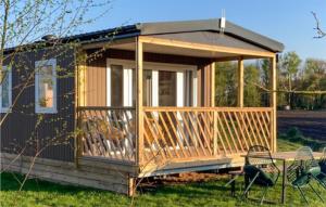 une petite cabine avec une terrasse couverte et des chaises dans la pelouse dans l'établissement Elperhof Lodge 1, à Schoonloo