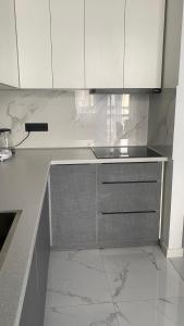 a kitchen with white cabinets and marble counter tops at Heaven Apartment Mountain View in Almaty