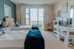 a bedroom with two beds and a desk and a window at Pinnacle Point Lodge 21 in Mossel Bay