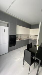 a kitchen with a table and a white refrigerator at Heaven Apartment Mountain View in Almaty