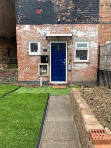 a brick house with a blue door in a yard at Limpenny Garden Flat in Nottingham