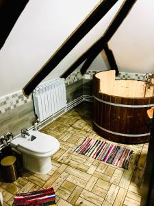 a bathroom with a toilet and a wooden tub at Casa Gabriel in Frumosu