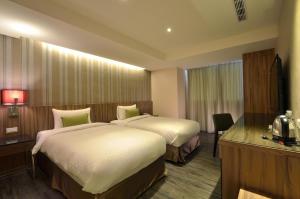 Una habitación de hotel con dos camas y un televisor. en 欣欣時尚旅店松山站, en Taipéi 17 fotos más