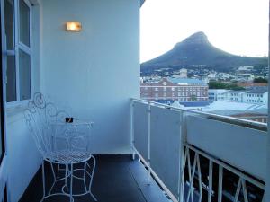 balcón con silla y vistas a la montaña en Overbeek 1 Bedroom 702 Apartment on Kloof Street, en Ciudad del Cabo