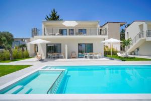 a villa with a swimming pool in front of a house at Filoxenia Luxury Apartments in Potos